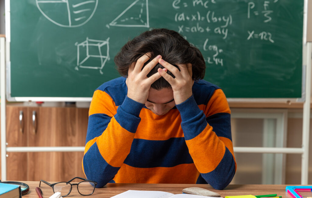 Stressed student preparing for exams in classroom"