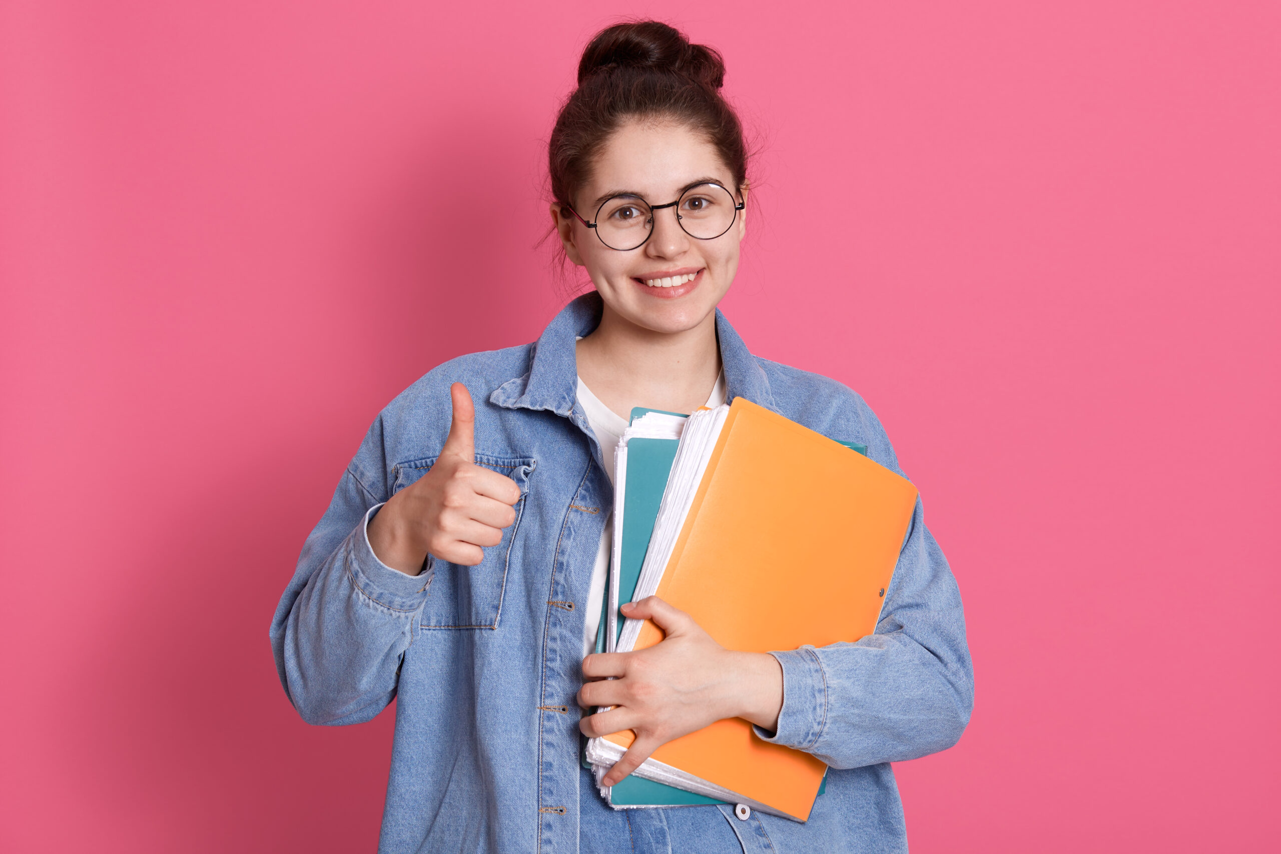 Happy student holding books and showing thumbs up after exam preparation
